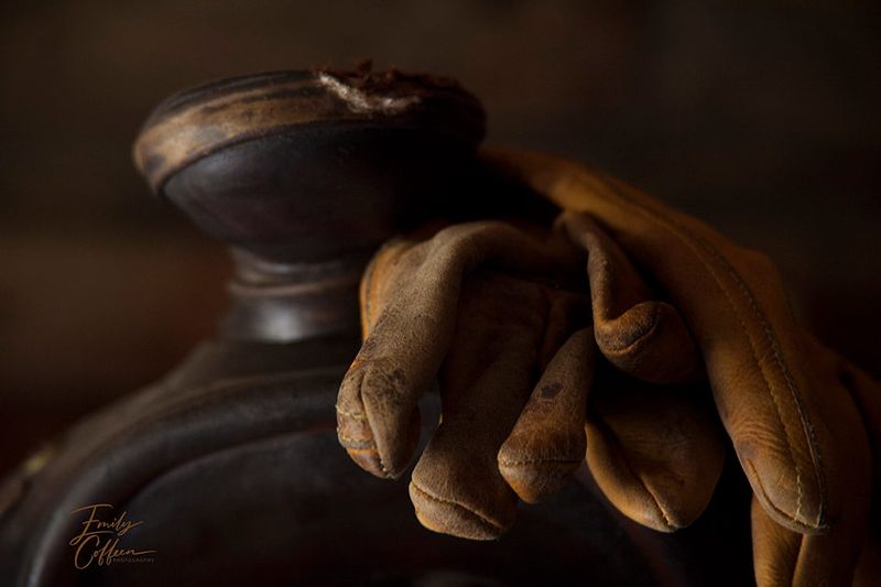 Worn leather work gloves resting on a saddle horn — western photography by Emily Coffeen